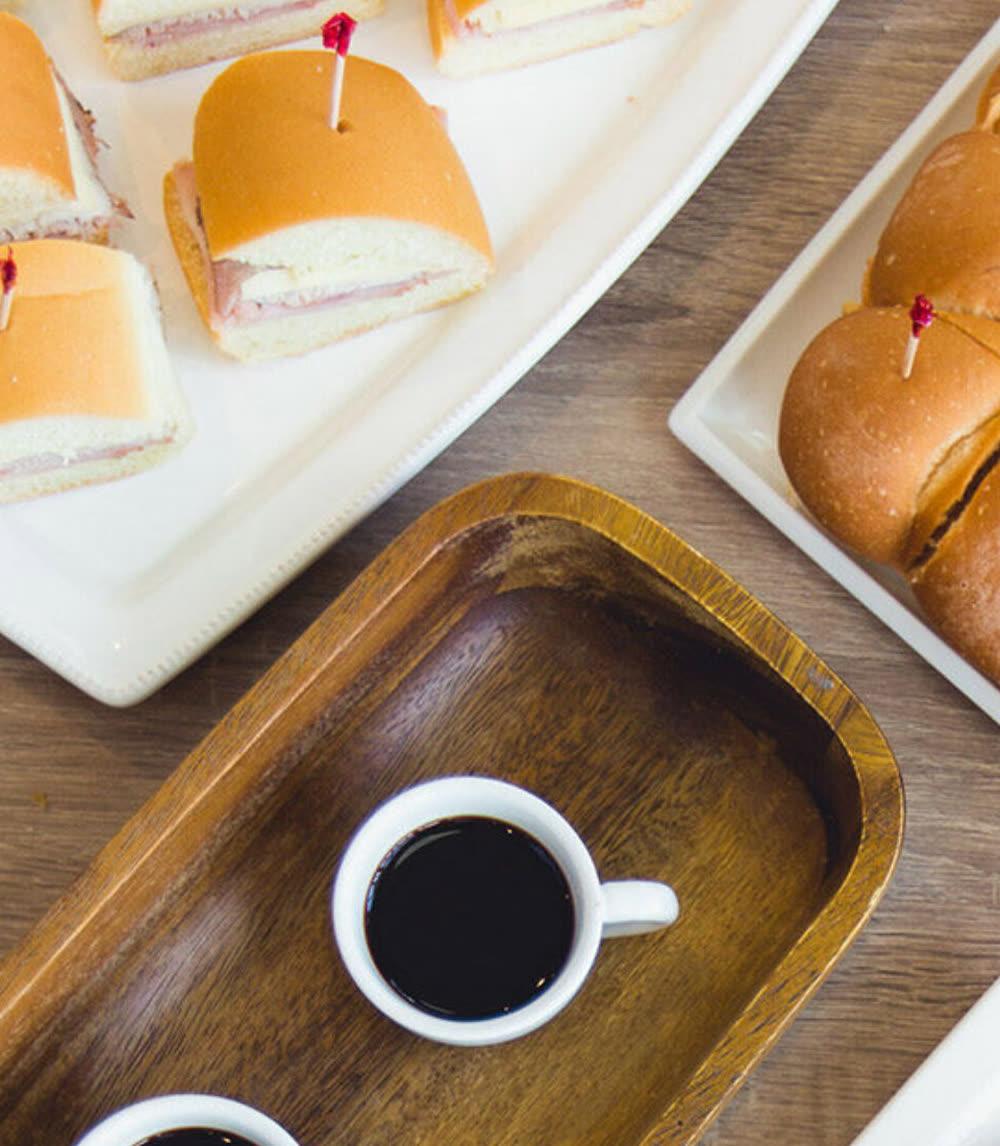 Cuban sandwich sliders on tray with cafecito.